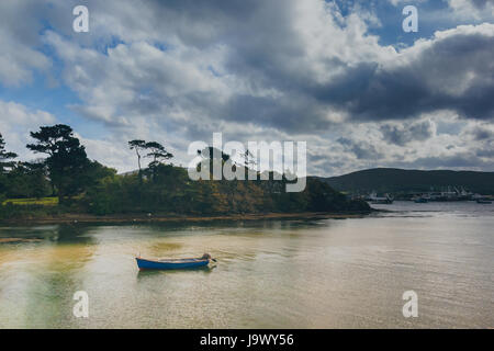 Le décor d'un lac avec les forêts, ciel bleu avec un bateau de pêche dans l'avant-plan. Banque D'Images