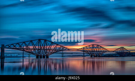 Forth Rail Bridge enjambant le Firth of Forth, Edinburgh South Queensferry,avec magnifique coucher de soleil pour un arrière-plan tout cet ensemble avec des réflexions. Banque D'Images