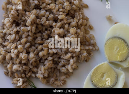 Orge perlé et œufs durs dans une assiette blanche. Banque D'Images