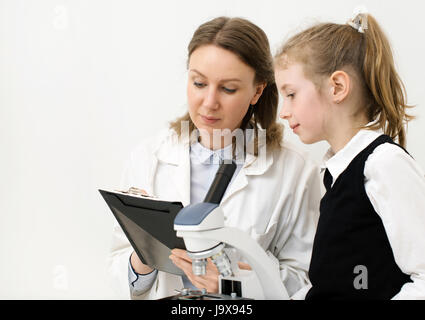 Femme et petite fille using microscope in laboratory. Banque D'Images