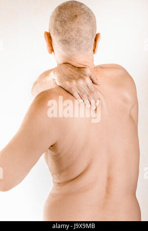 Homme massant sa page retour, le muscle trapèze, à cause d'une vertèbre thoracique douleur due à un déplacement d'une vertèbre dorsale frottant sur un nerf Banque D'Images