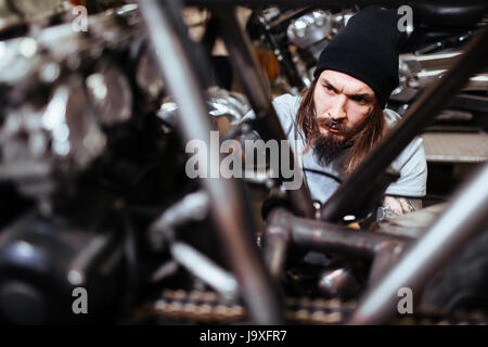 Portrait de l'accent tattooed man travaillant dans un garage moto tuning haut Banque D'Images