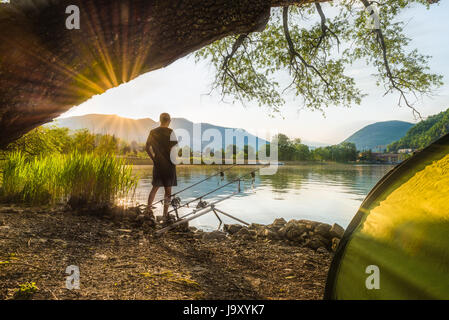 Aventures de pêche, pêche à la carpe. Angler, au coucher du soleil, est la pêche avec carpfishing technique. Camping sur la rive du lac Banque D'Images