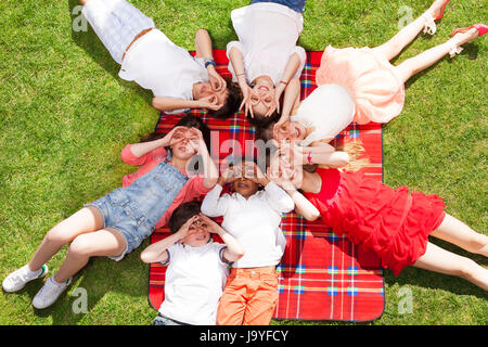 Les enfants portant sur l'herbe et faisant un geste lunettes Banque D'Images