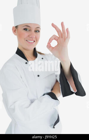 Portrait of happy female chef showing ok sign over white background Banque D'Images