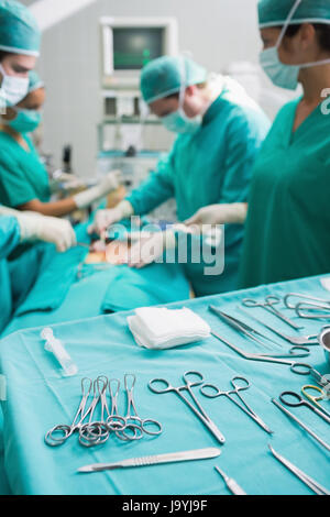 Outils chirurgicaux affichée sur un plateau chirurgical tandis que les chirurgiens opèrent dans un hôpital Banque D'Images