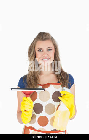 Portrait of smiling young maid holding spray désinfectant et de l'essuie-glace sur fond blanc Banque D'Images