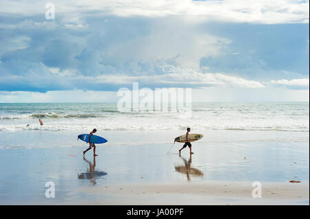 L'île de Bali, Indonésie - Mars 16, 2013 : Local qui se promenaient avec un surf sur la plage. Bali est l'un des top des destinations monde de surf. Banque D'Images