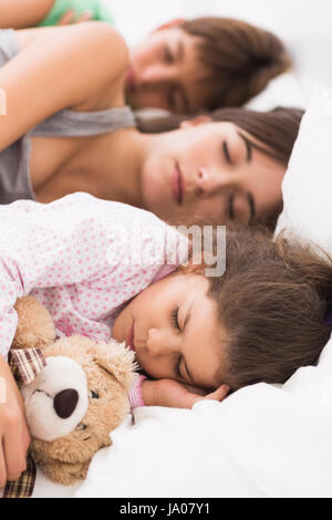 Mère et enfants à cajoler jusqu'au lit endormi Banque D'Images