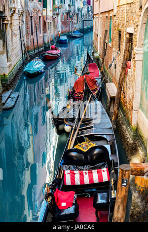 À Venise, Italie, scène colorée de deux gondoles amarré le long d'un canal avec des reflets de l'architecture dans l'eau et des bateaux à moteur. Banque D'Images