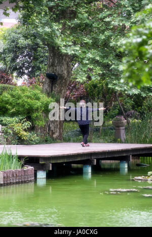 Vieille Femme faisant de tai chi dans le parc de Jing'an, Shanghai, Chine Banque D'Images