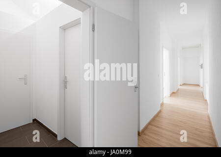 Intérieur immobilier - nouveau corridor vide, murs blancs et les portes et plancher en bois