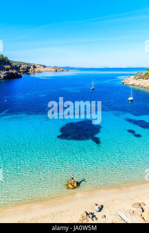 La plage de Cala Salada, IBIZA ISLAND - 17 MAI 2017 : man taking photo of young woman standing on rock dans l'eau de mer sur la belle plage de Cala Salada bay, JE Banque D'Images