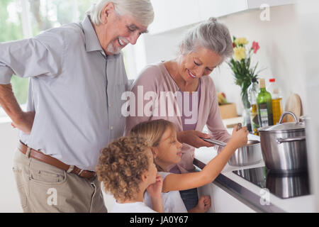 Heureusement les enfants avec les grands-parents de cuisson dans la cuisine Banque D'Images