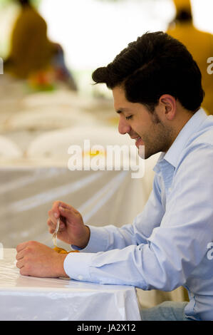 Beau jeune businessman eating a des beignets avec du sucre et de ses composants Banque D'Images