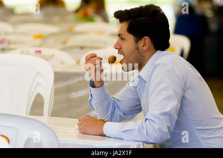 Beau jeune businessman eating a des beignets avec du sucre et de ses composants Banque D'Images