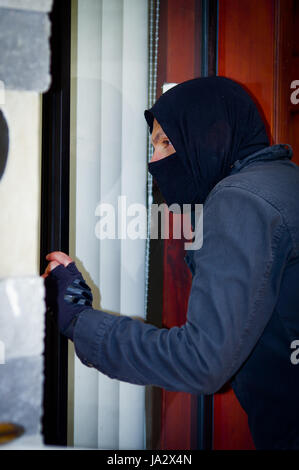 Cambrioleur avec port d'un masque qui tentent d'entrer dans la chambre Banque D'Images