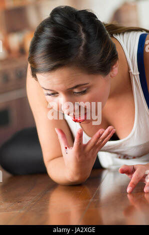 Belle jeune femme le saignement de son nez, sur plancher en bois Banque D'Images