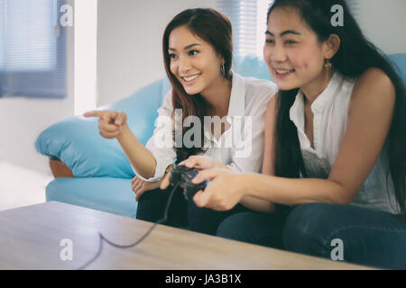 Deux femmes amis concurrentiel jouer à des jeux vidéo et de bonne humeur à la maison heureux excité Banque D'Images