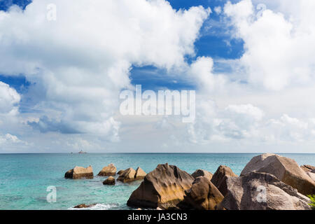 Rocky côte nord de La Digue, aux Seychelles avec une petite île dans l'arrière-plan Banque D'Images