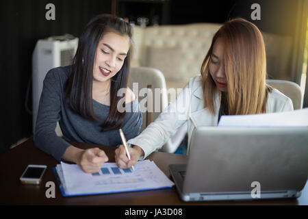 Deux femmes d'affaires de l'Asie à l'aide de l'ordinateur portable et la discussion de l'important contrat au bureau ,soft focus Banque D'Images
