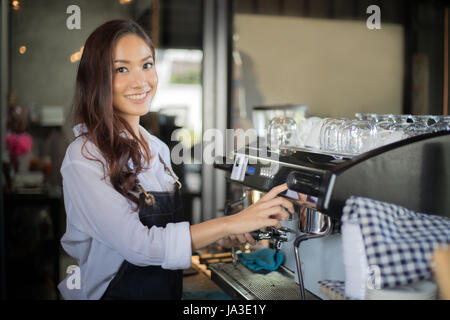 Asian women smiling Barista et à l'aide d'une machine à café dans le café au comptoir - femme au travail propriétaire de petite entreprise nourriture et boisson cafe concept Banque D'Images