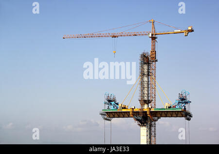 Pont du pont à haubans d'être érigée sur deux côtés d'un grand pilier de béton à l'aide de grues à tour le pont sur la rivière Mandovi à Goa, Inde. Banque D'Images