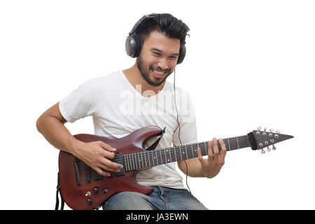 Beau jeune homme asiatique qui joue de la guitare et écouter de la musique avec des casques, Flou et soft focus Banque D'Images