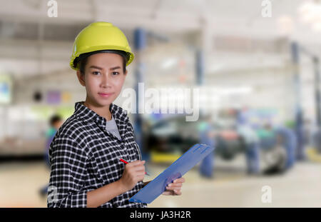 Ingénieurs et techniciens des femmes asiatiques sont mécanicien contrôle et inspectingthe liste sur le conseil d'une voiture en atelier de réparation automobile Banque D'Images