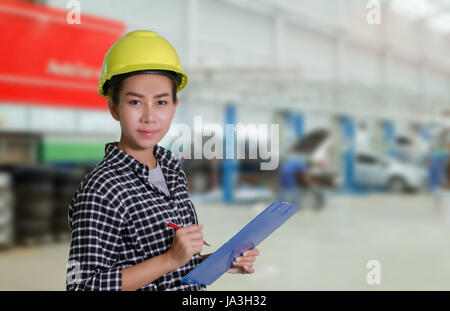 Ingénieurs et techniciens des femmes asiatiques sont mécanicien contrôle et inspectingthe liste sur le conseil d'une voiture en atelier de réparation automobile Banque D'Images