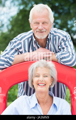 Senior couple on children's slide Banque D'Images