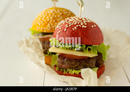 Des hamburgers en rouge et jaune sur les pains de table en bois blanc, selective focus Banque D'Images