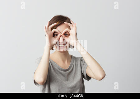 Pretty girl holding doigts près des yeux comme lunettes : comme masque de super héros ou owl Banque D'Images