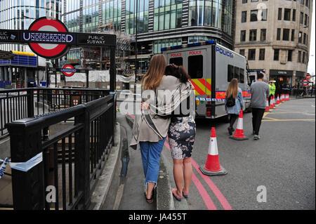 Deux femmes hug après apporter des fleurs pour ajouter aux hommages mis sur le côté nord de London Bridge à la suite de la nuit dernière, l'incident terroriste. Banque D'Images