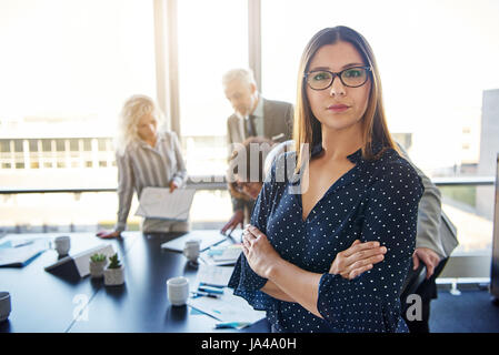 Femme d'affaires graves devant team, looking at camera Banque D'Images