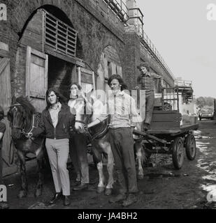 Années 1970, histroical, groupe de jeunes mâles adultes à bascule ou un chiffon et d'os les hommes avec leur cheval et de charrettes à l'extérieur de leur dépôt à l'ancienne gare des arcs, le sud de Londres, Angleterre, Royaume-Uni. Banque D'Images