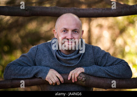 Un homme chauve dans un pull, s'assoit et se repose sur la nature Banque D'Images