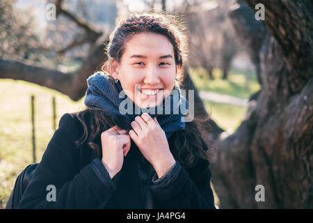 Portrait d'une fille heureuse d'Asie. Elle regarde la caméra et sourit, enveloppé dans une écharpe. Banque D'Images