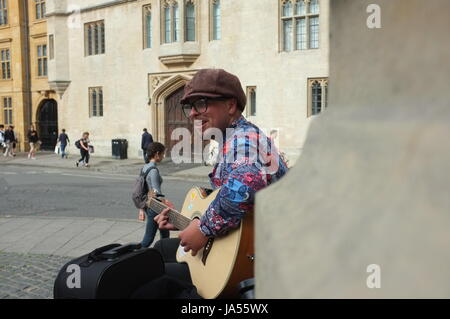 Un homme jouant une guitare acoustique sur le Mémorial des martyrs à Oxford, Angleterre, Royaume-Uni. Le 2 juin 2017. Banque D'Images