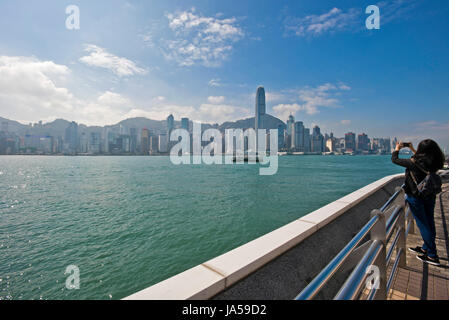 Vue horizontale d'un touriste sur Kowloon à prendre des photos de la ligne d'horizon spectaculaire de l'île de Hong Kong, Chine. Banque D'Images