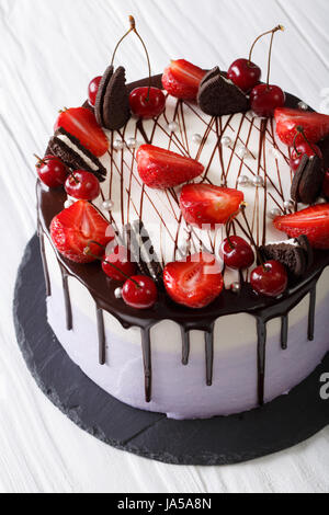 Beau cheesecake aux fraises et cerises, décoré avec des biscuits sur la table verticale. Banque D'Images