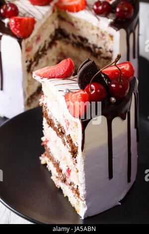 Tranche de gâteau avec des fraises et des cerises et du chocolat sur une plaque verticale. Banque D'Images