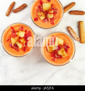 Un carré photo prise à la verticale d'un traditionnel espagnol, salmorejo soupe froide, servi dans des verres avec des bâtonnets de pain, garnie de jambon et croûtons Banque D'Images