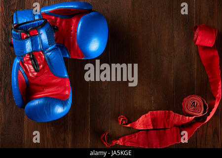 Arrière-plan de Sport bleu et rouge avec des gants et un bandage rouge sur fond de bois. Banque D'Images