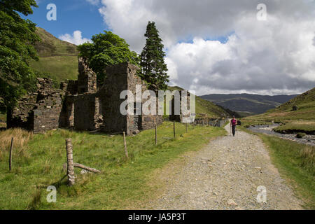 Female hiker en passant devant les ruines d'un bâtiment sur le chemin, menant Watkin à Snowdon, le plus haut sommet dans le parc national de Snowdonia au Pays de Galles. Banque D'Images