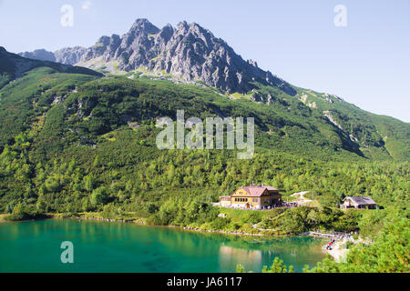 Scenic lake landscape view of house in the High Tatras mountains in Slovakia with a high peak in the background in a travel and tourism concept Banque D'Images