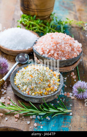 Différents types de sel naturel dans des bols en pierre sur la surface en bois. Sel de mer blanche, rose sel de l'Himalaya, sel épicé au romarin Banque D'Images