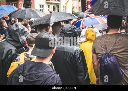 Groupe de jeunes de derrière la marche dans la pluie avec parasols Banque D'Images