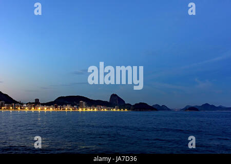 La plage de Copacabana et le Pain de Sucre vu la nuit avec ses bâtiments, l'éclairage, la mer, les collines et les contours Banque D'Images