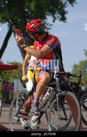 Spring City, Utah, USA - 2 août 2006 : l'homme assis sur son vélo de route offrant une barre d'alimentation à son coéquipier au début de la course. Les cyclistes attendre Banque D'Images